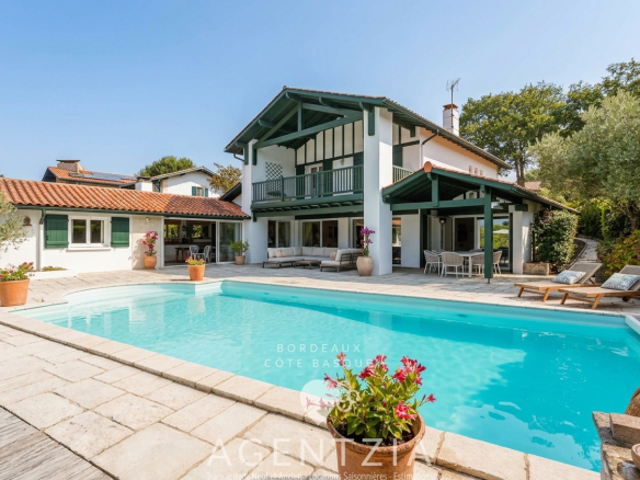 Villa de standing avec piscine et jardin à Bassussarry, entourée de verdure.
