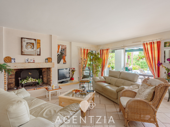 Intérieur d'une villa avec salon lumineux, cheminée et accès au jardin.