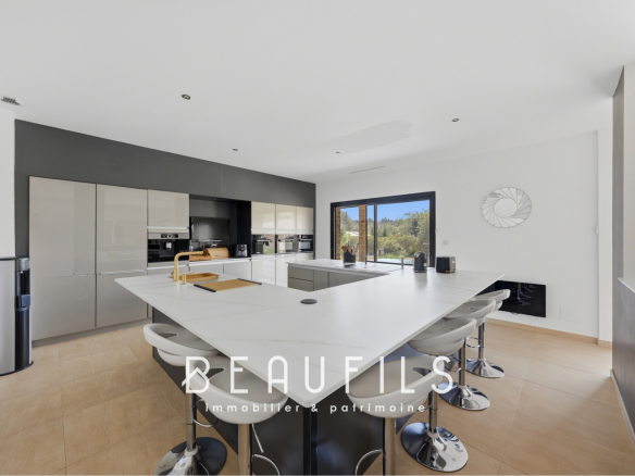Modern and spacious villa kitchen with central island and large windows.
