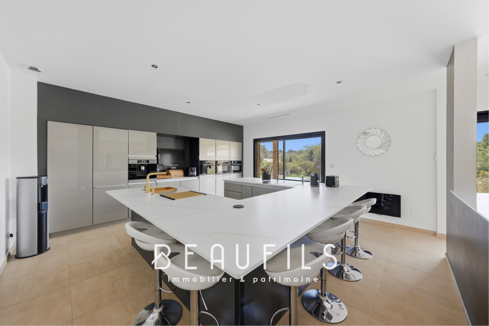 Modern and spacious villa kitchen with central island and large windows.