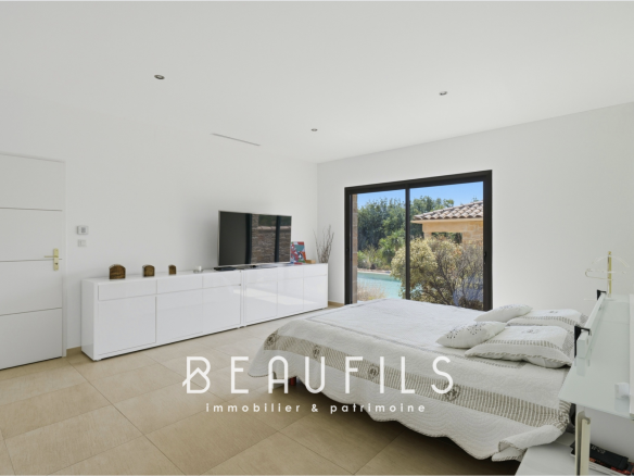 Spacious room with bed and television, open to the outside, in a modern villa.