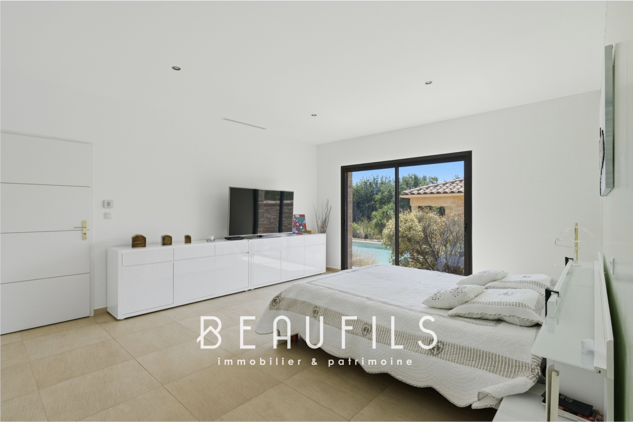 Spacious room with bed and television, open to the outside, in a modern villa.