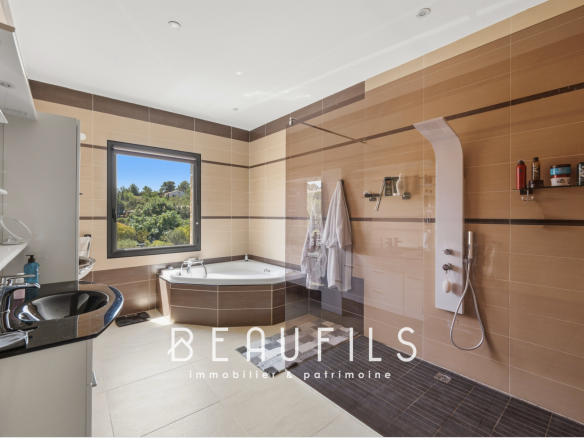 Modern bathroom with bath and shower, window overlooking nature.