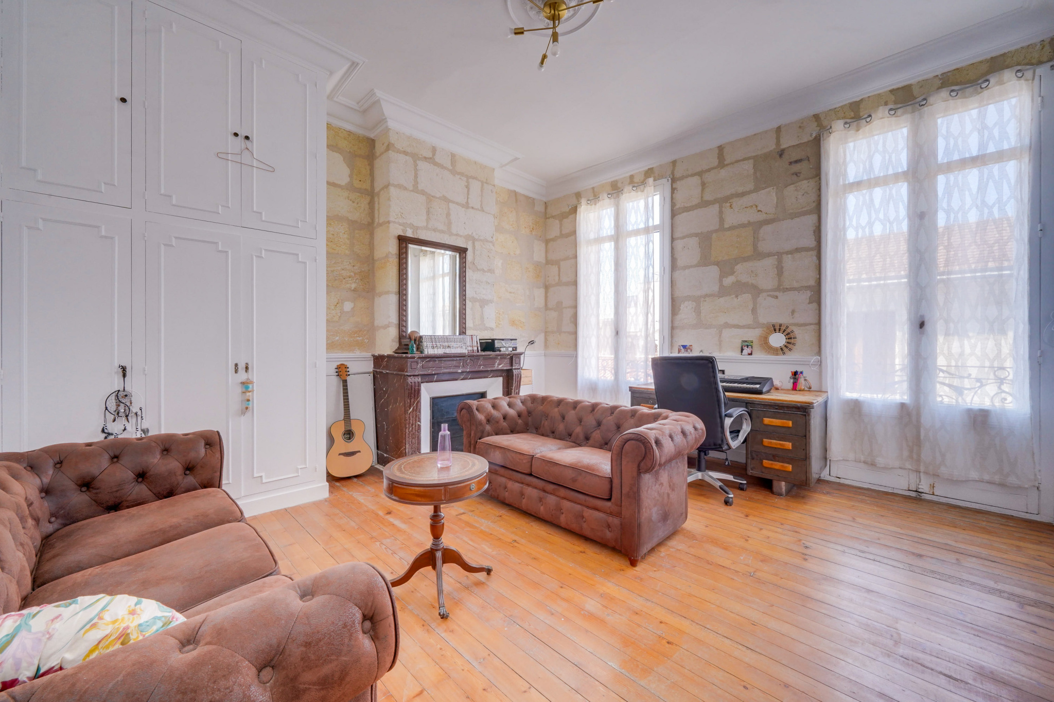 Salon d’une maison bourgeoise à Bordeaux Salon d'une maison bourgeoise à Bordeaux avec canapé en cuir et cheminée en pierre.
