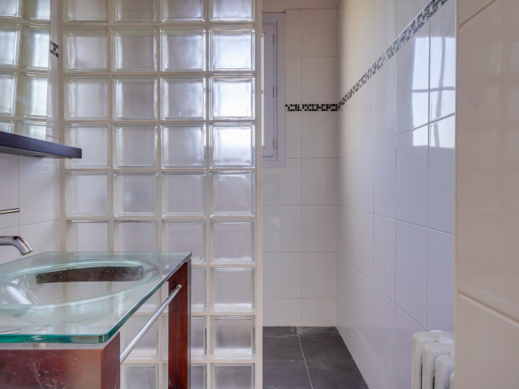 Salle de bain moderne avec murs en carreaux de verre et lavabo en verre.