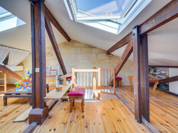 Intérieur d'une maison avec poutres apparentes et lumière naturelle, espace de vie avec jeux pour enfants.