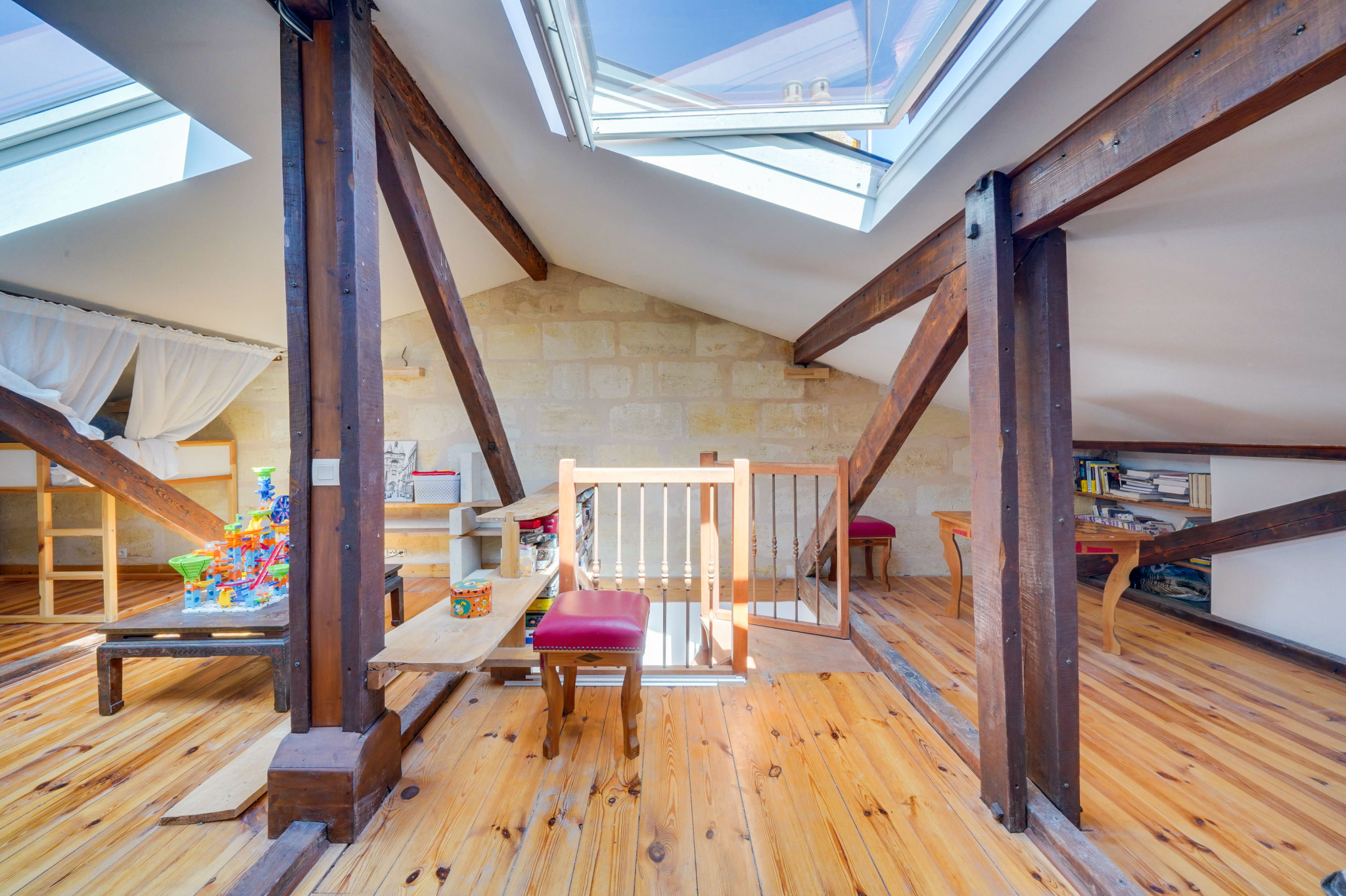 Intérieur d’une maison bourgeoise à Bordeaux Intérieur d'une maison avec poutres apparentes et lumière naturelle, espace de vie avec jeux pour enfants.
