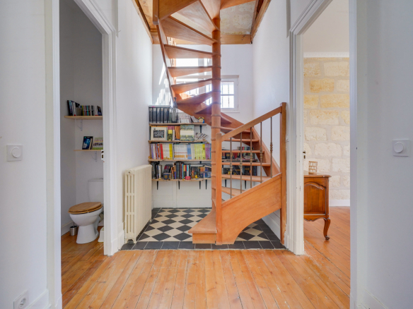 Intérieur d'une maison bourgeoise à Bordeaux avec un escalier en bois et des murs clairs.