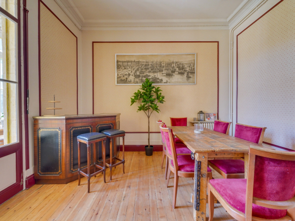Intérieur d'une maison bourgeoise à Bordeaux, avec une table en bois et des chaises rouges dans une salle à manger.