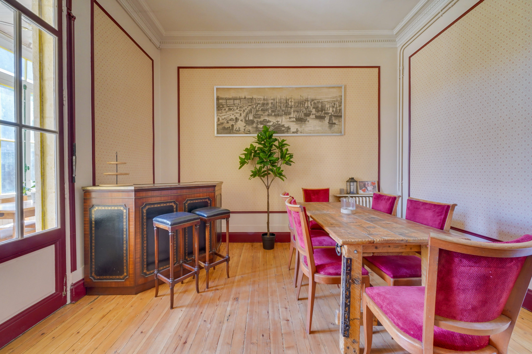Salle à manger d’une maison bourgeoise à Bordeaux Intérieur d'une maison bourgeoise à Bordeaux, avec une table en bois et des chaises rouges dans une salle à manger.