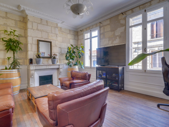 Salon d'une maison bourgeoise à Bordeaux avec murs en pierre et mobilier en cuir.