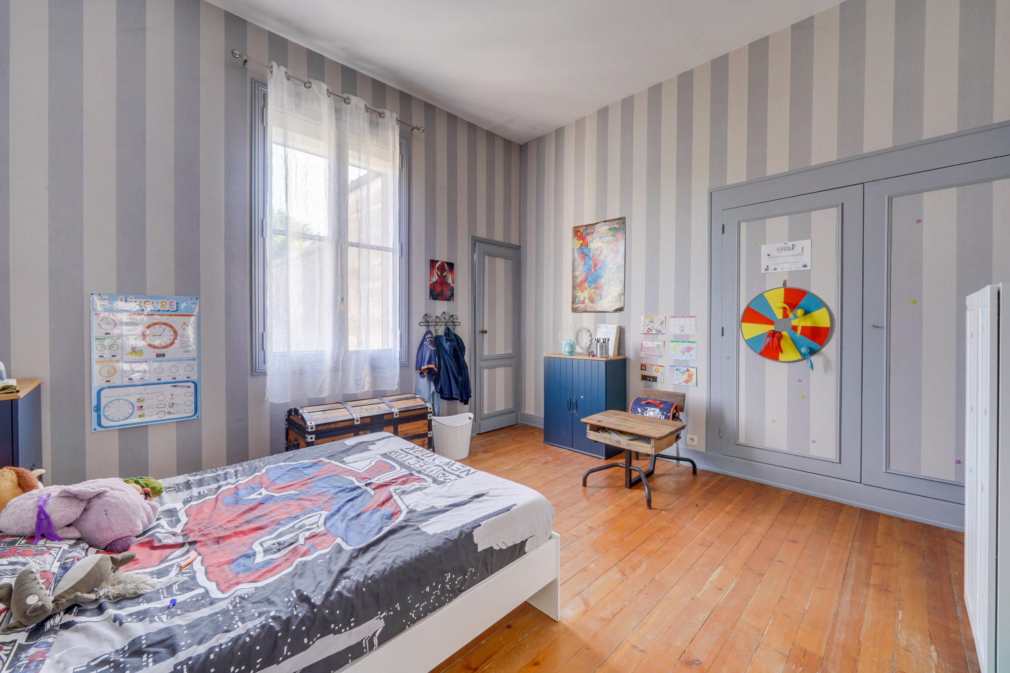 Chambre dans une maison bourgeoise à Bordeaux Chambre d'une maison bourgeoise à Bordeaux avec des murs rayés et un lit avec des draps colorés.