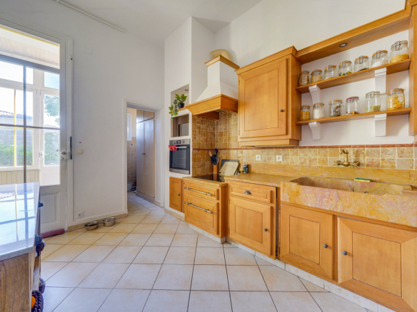 Cuisine d'une maison bourgeoise avec meubles en bois et carrelage au sol à Bordeaux.
