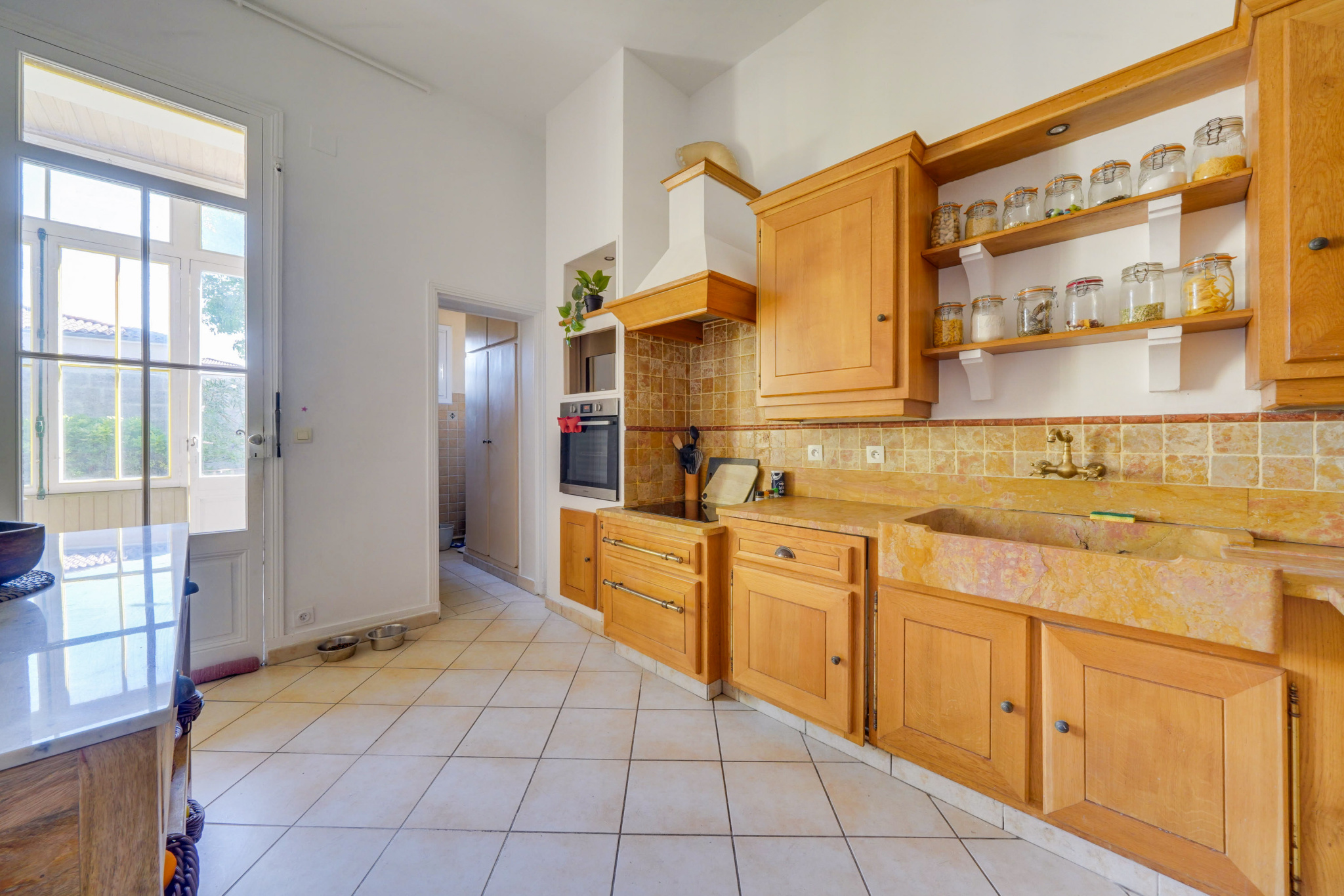 Cuisine d’une maison à Bordeaux Cuisine d'une maison bourgeoise avec meubles en bois et carrelage au sol à Bordeaux.