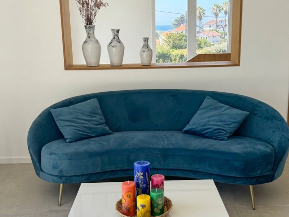Intérieur d'une villa à Bidart avec un canapé bleu, des coussins, des bougies colorées et un miroir.