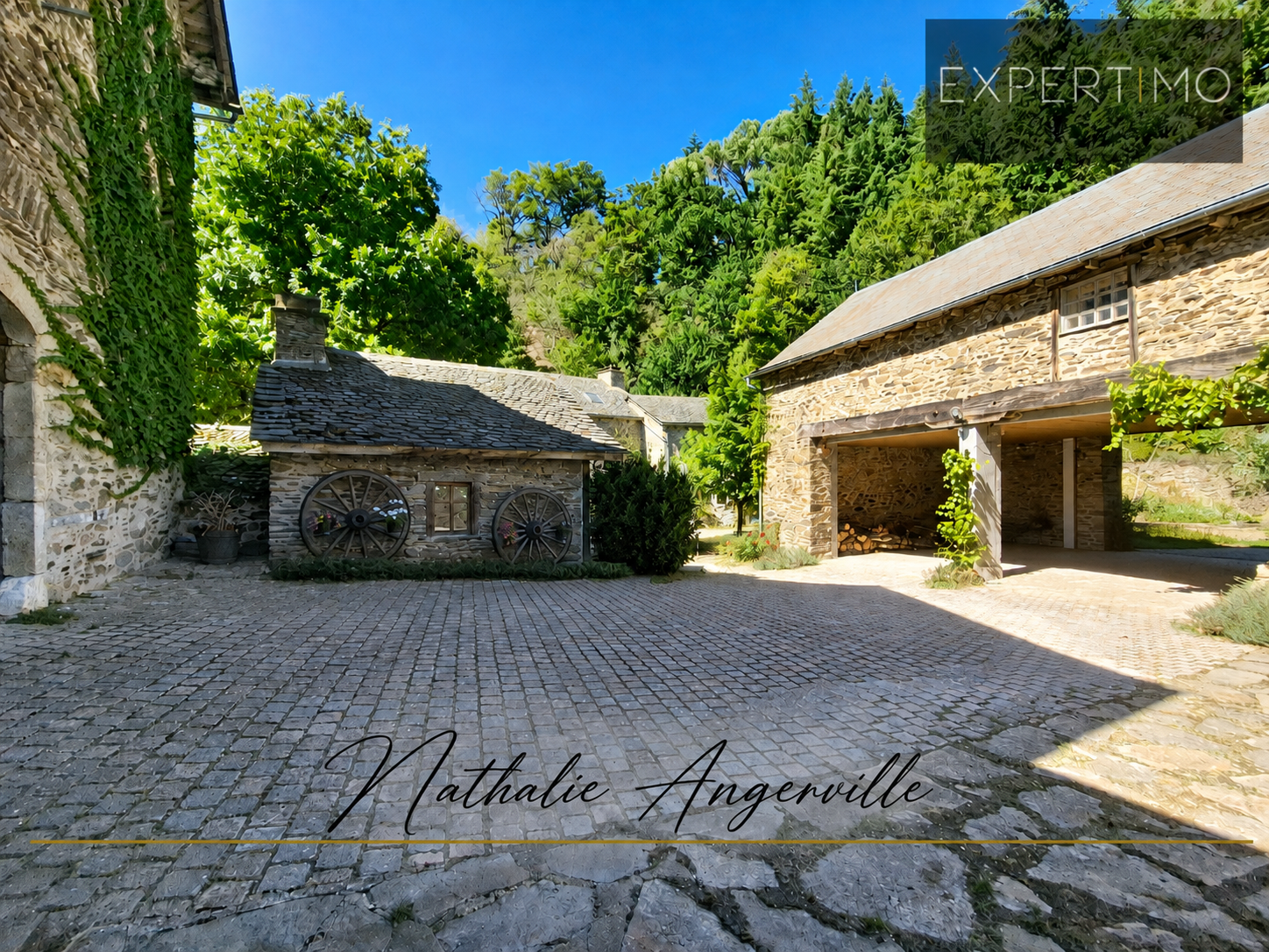 Property with old mill in Salmiech Former mill and outbuildings in a stone courtyard, surrounded by green trees.