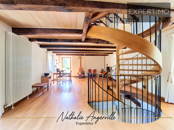 Interior of a property with a wooden spiral staircase and exposed beams.