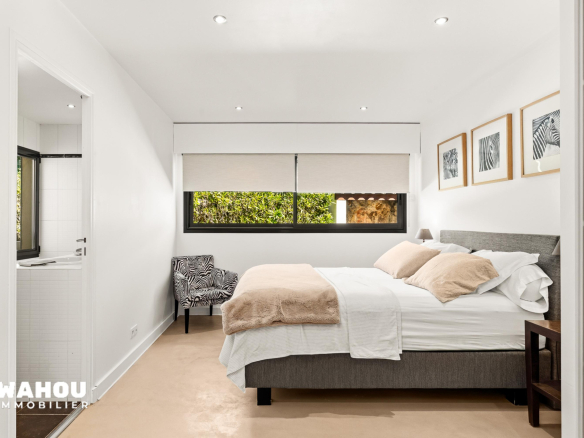 Modern room with double bed and armchair, natural light in Adrets-de-l'Estérel.