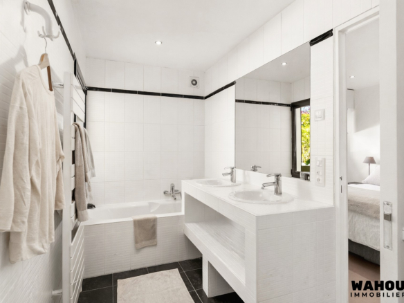 Modern bathroom with bathtub and double sink, decorated in black and white.
