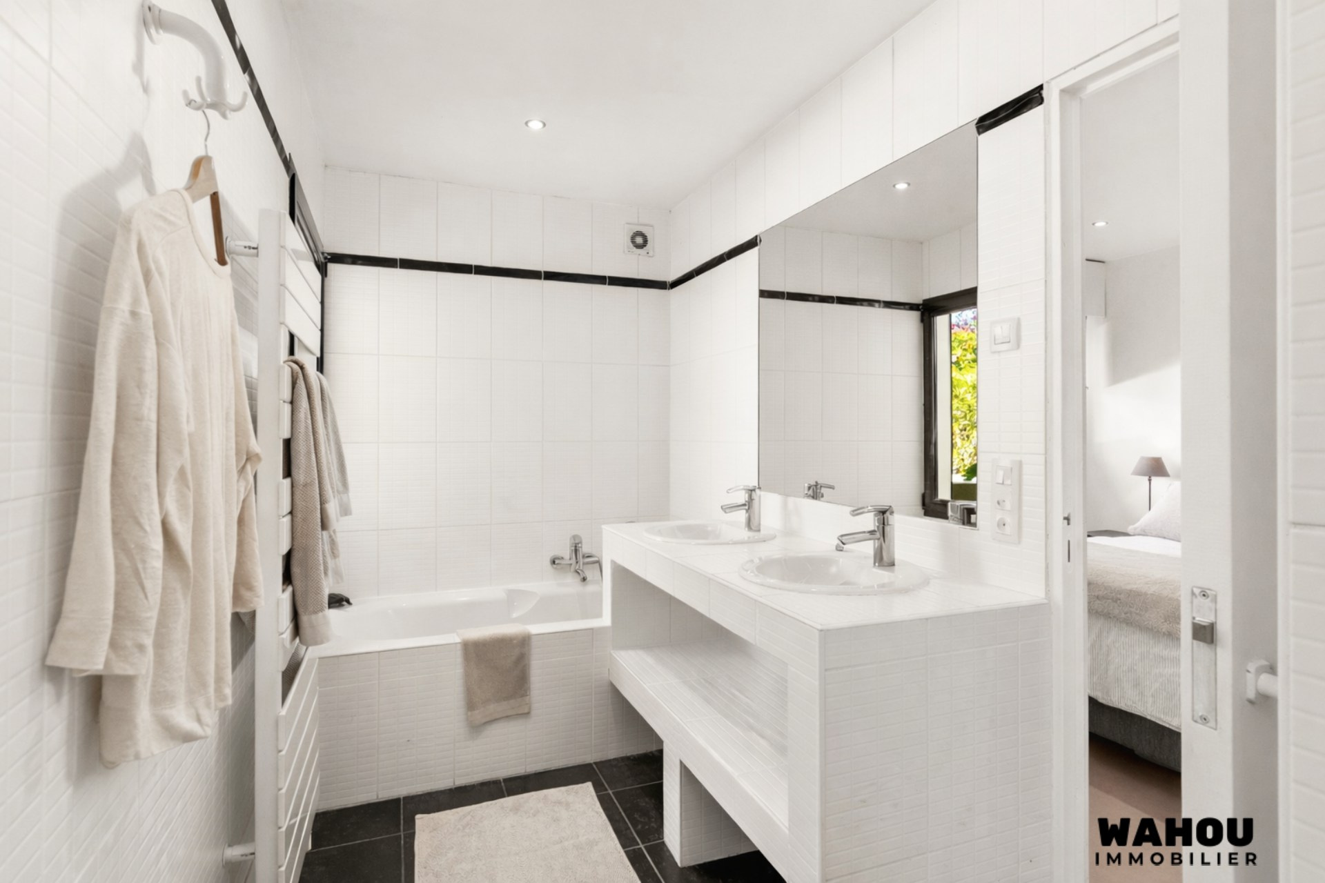 Modern bathroom with bathtub and double sink, decorated in black and white.