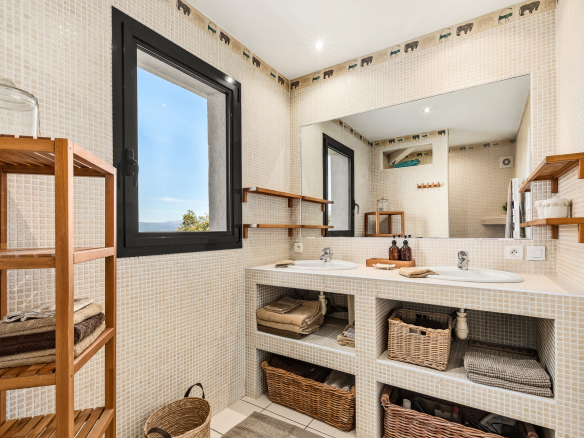 Modern bathroom with double sink and wooden storage, view of the outside.