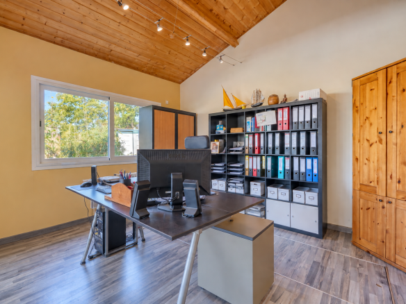Bureau dans une maison avec un bureau en bois et des rangements, fenêtres avec vue sur l'extérieur.