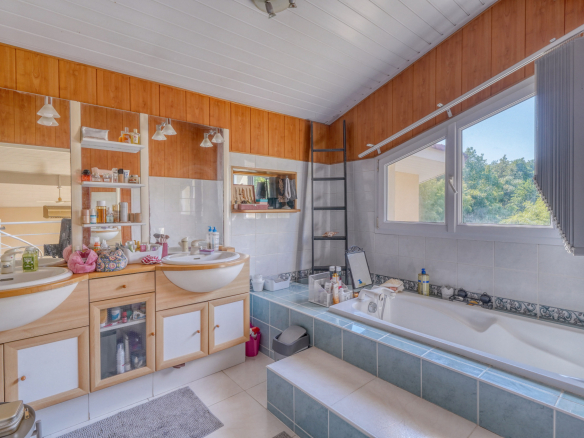 Salle de bains spacieuse avec baignoire et double vasque dans une maison familiale.