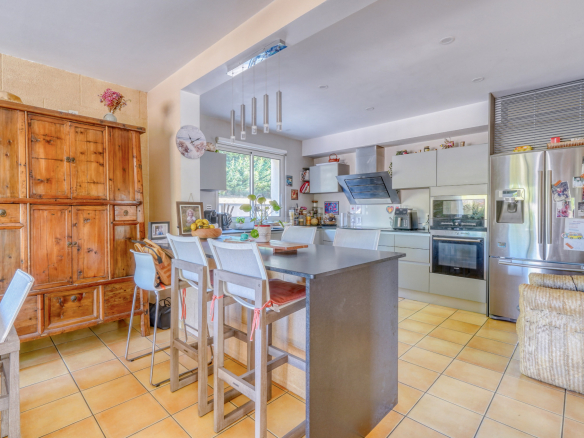 Cuisine moderne avec îlot central et coin repas dans une maison familiale à Montussan.