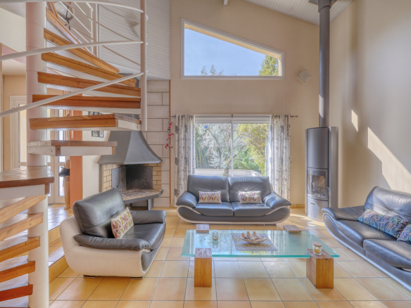 Intérieur d'une maison avec salon lumineux, cheminée et poêle à bois.