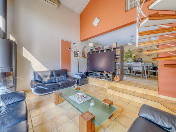 Intérieur d'une maison avec salon, cheminée et escalier en colimaçon.