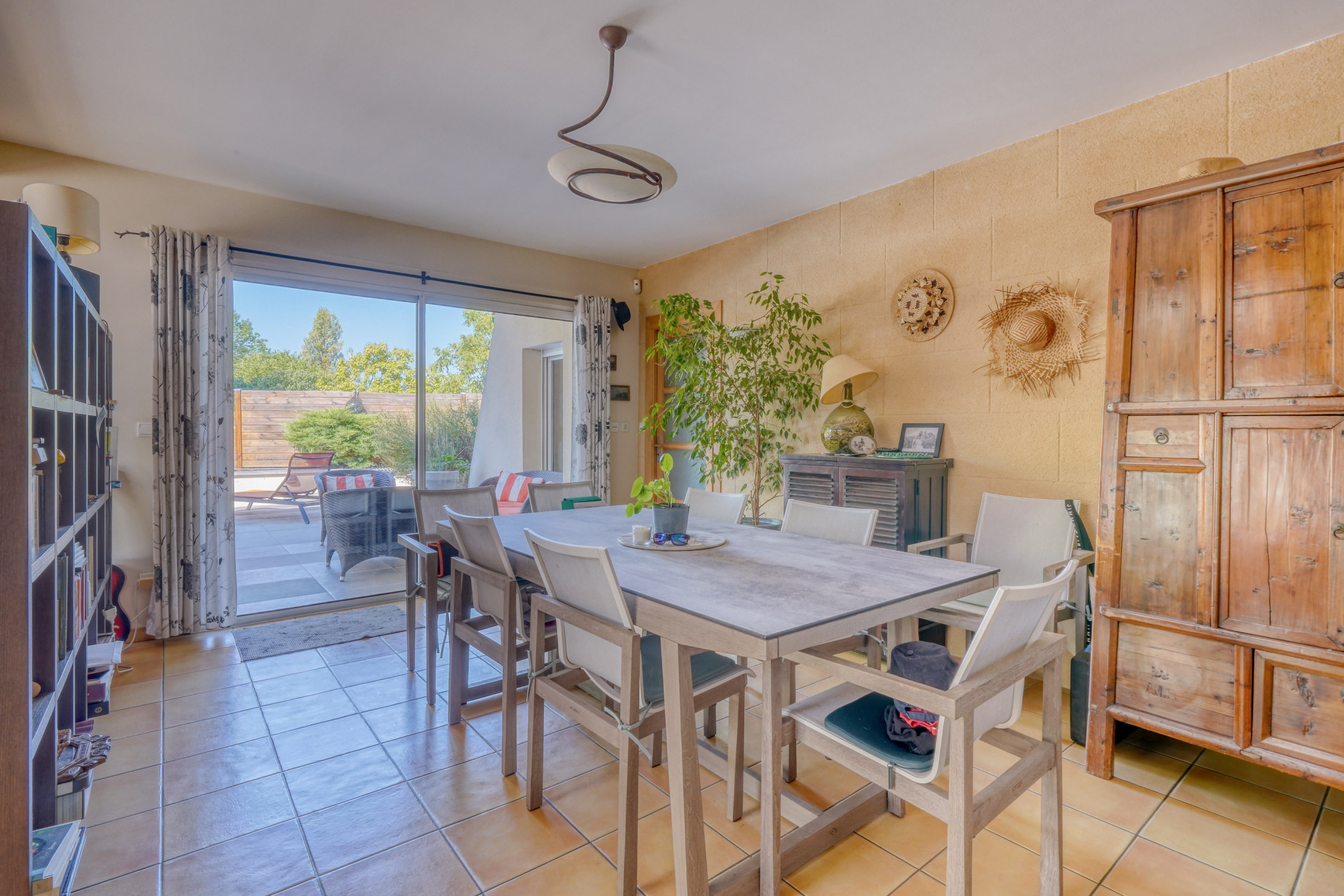 Salle à manger dans une maison à Montussan Salle à manger lumineuse avec table et chaises, fenêtres donnant sur l'extérieur.