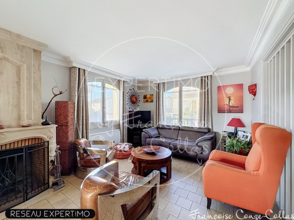 Intérieur d'un salon spacieux avec cheminée, canapé et fauteuils, lumineux.