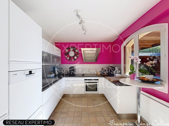 Cuisine moderne avec murs roses et équipements intégrés, éclairage par spots.