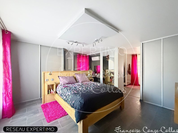 Chambre spacieuse avec lit en bois, décoration moderne et fenêtres avec rideaux roses.