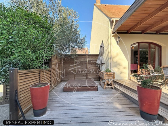 Terrasse en bois avec pots de fleurs devant une maison à Saint-Cyr-l'École.