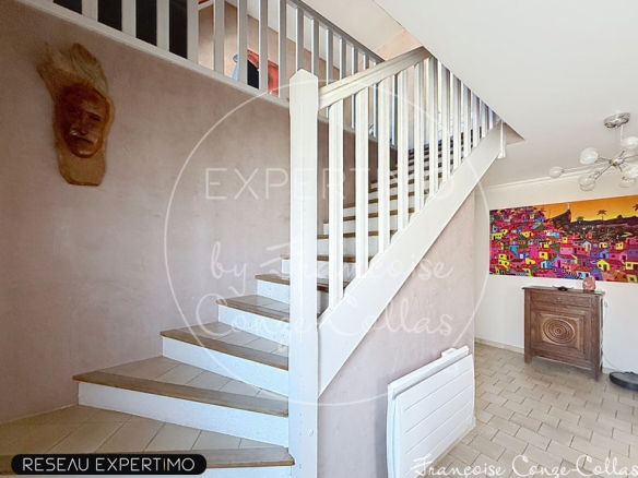 Intérieur d'une maison avec un escalier en bois et un mur décoré, éclairage moderne.
