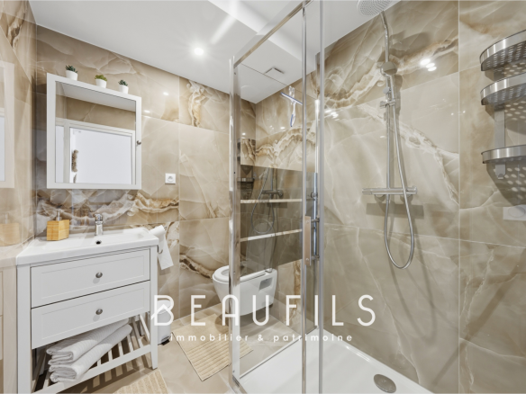 Salle de bain moderne avec douche, lavabo et miroir dans un appartement rénové.
