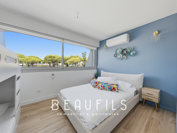 Chambre d'une marina rénovée avec lit double et décoration moderne, fenêtres offrant une vue sur l'extérieur.