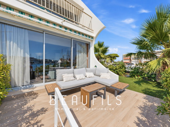 Terrasse d'une marina avec mobilier de jardin, vue sur le port et la végétation environnante au Grau-du-Roi.