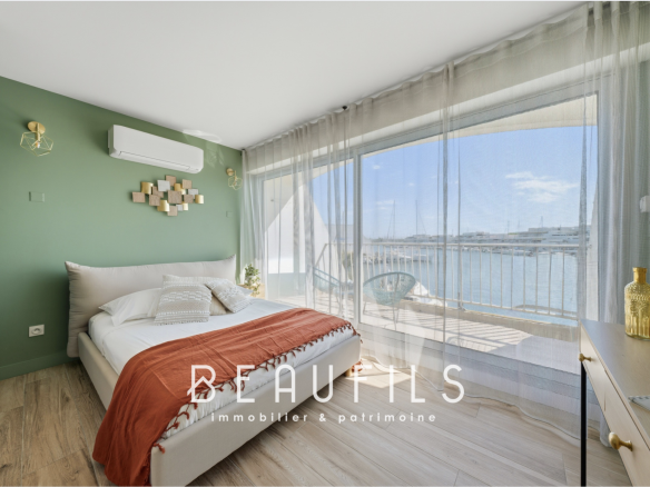 Chambre lumineuse avec vue sur la marina, fenêtres panoramiques et décoration moderne.