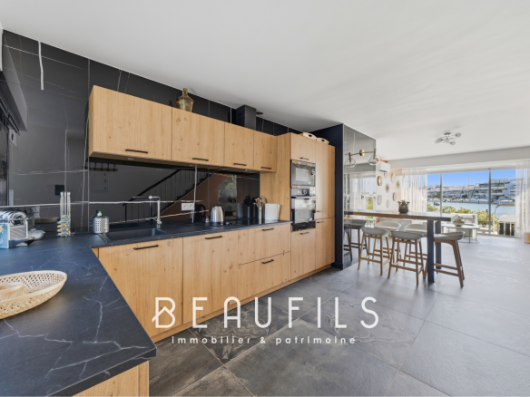 Cuisine moderne avec îlot central et vue sur l'extérieur dans une marina rénovée au Grau-du-Roi.