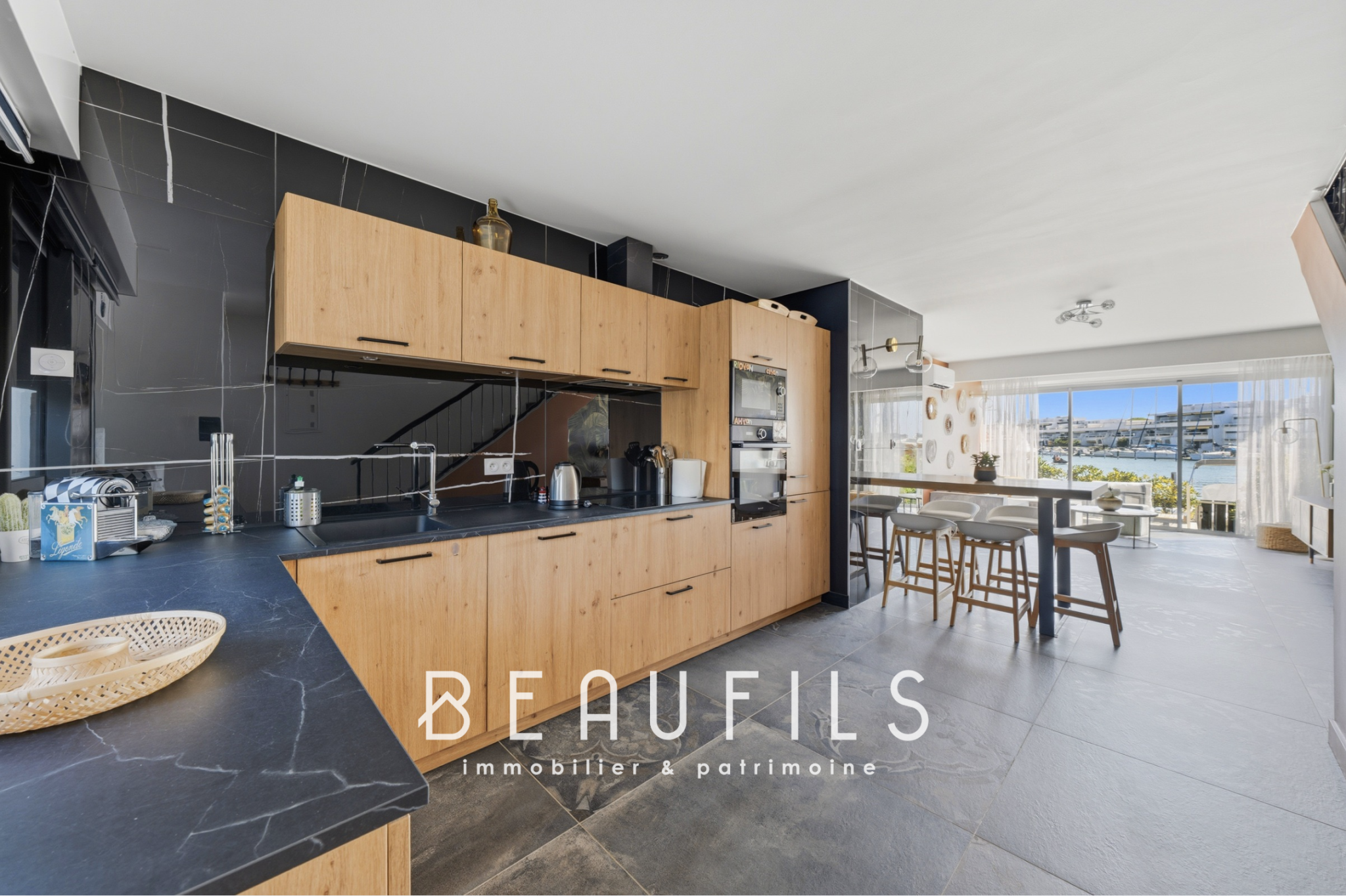 Cuisine d’une marina au Grau-du-Roi Cuisine moderne avec îlot central et vue sur l'extérieur dans une marina rénovée au Grau-du-Roi.