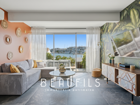 Intérieur d'un salon moderne avec vue sur la marina, décor tropical et mobilier contemporain.