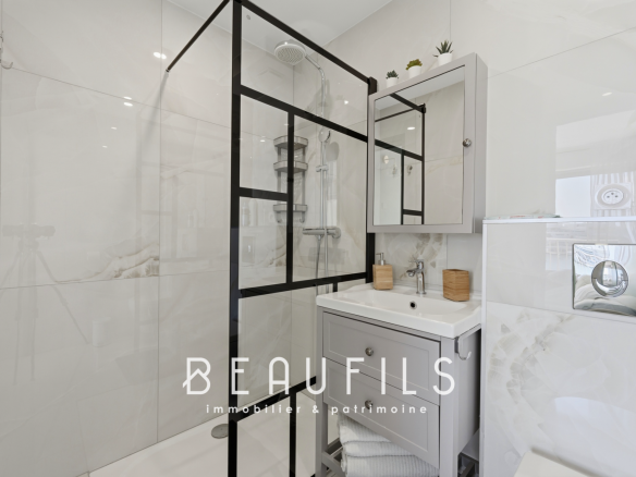 Salle de bain moderne avec douche en verre et meuble lavabo.