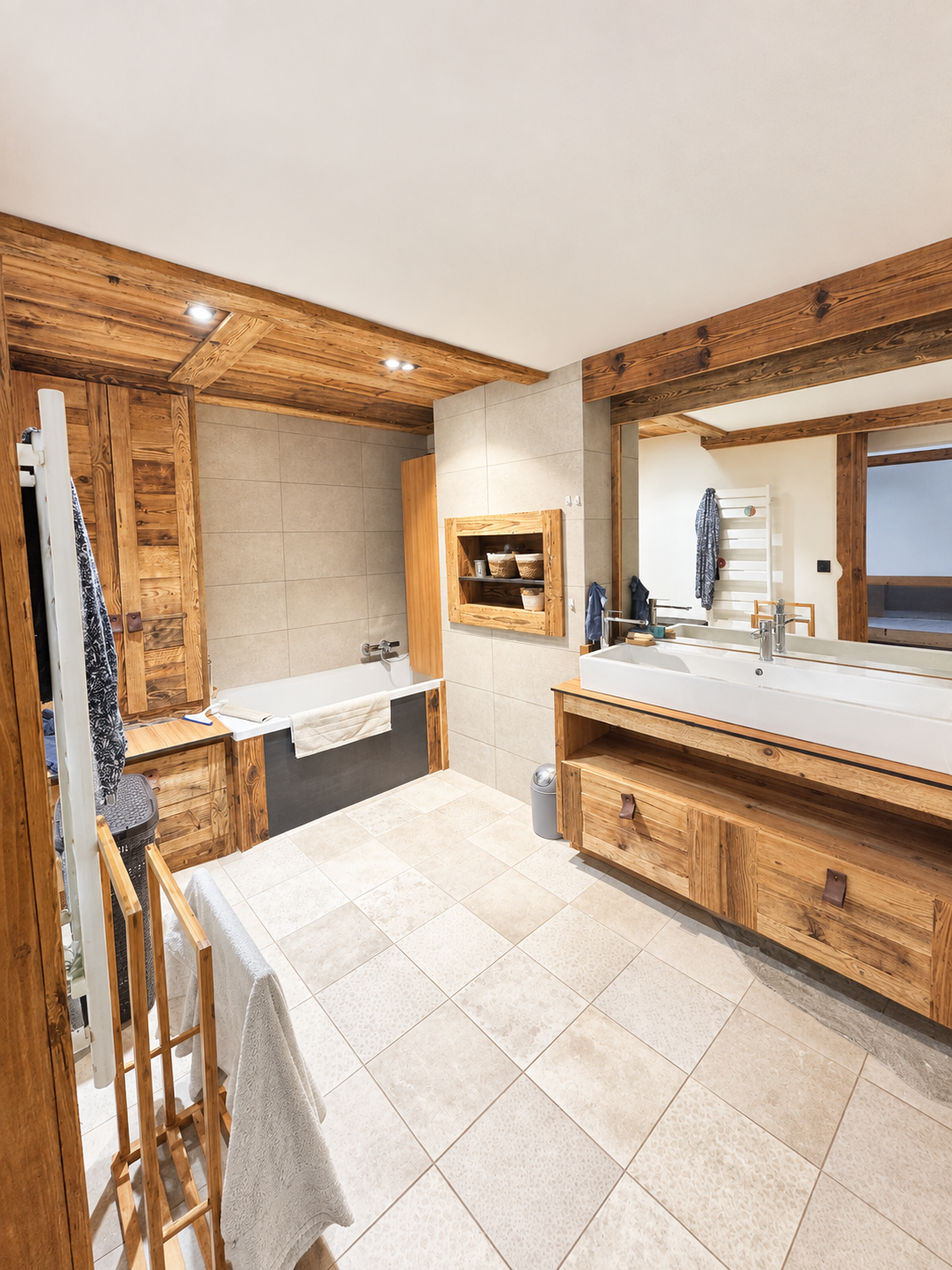 Salle de bain moderne en bois Salle de bain spacieuse avec baignoire et meuble en bois, carrelage clair, miroir et douche.