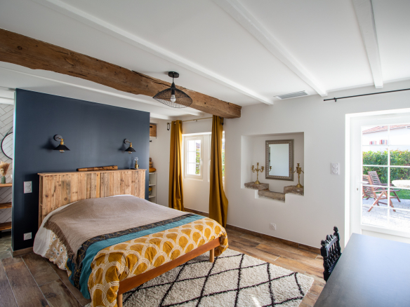 Chambre d'une maison rénovée avec lit, décoration moderne et accès à un patio.