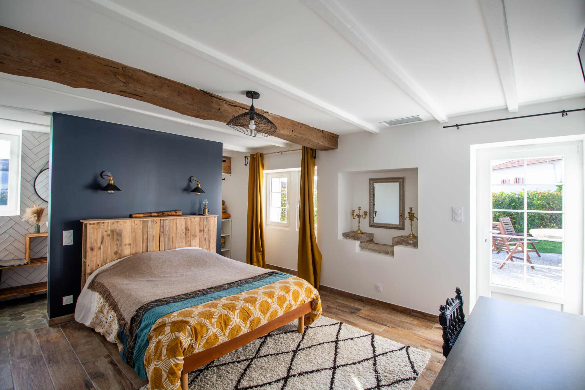 Chambre d'une maison rénovée avec lit, décoration moderne et accès à un patio.