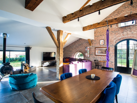 Intérieur d'une maison rénovée avec poutres apparentes, salon lumineux et coin repas.