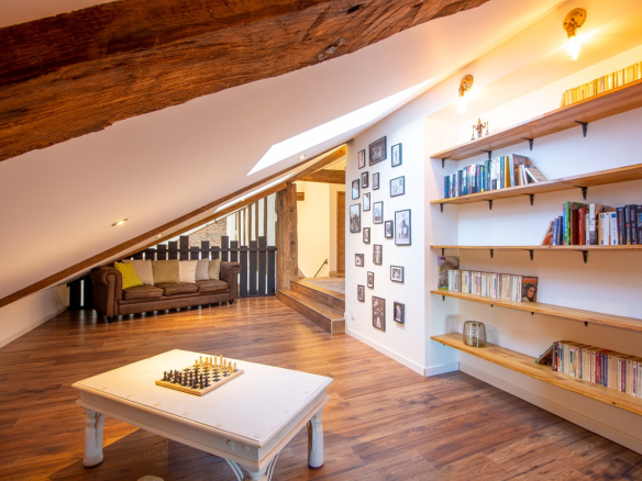 Intérieur d'une maison rénovée avec un coin salon, des étagères et un jeu d'échecs.