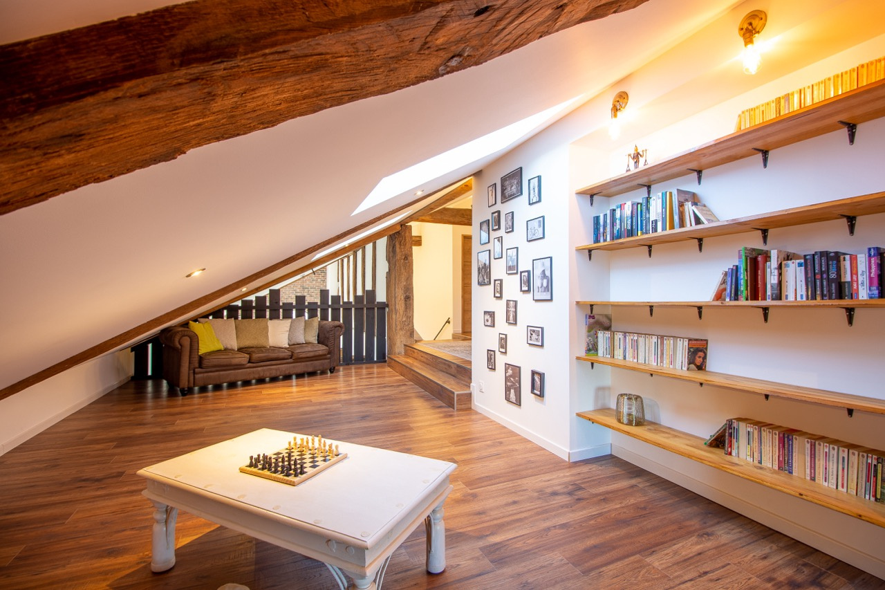 Intérieur d'une maison rénovée avec un coin salon, des étagères et un jeu d'échecs.
